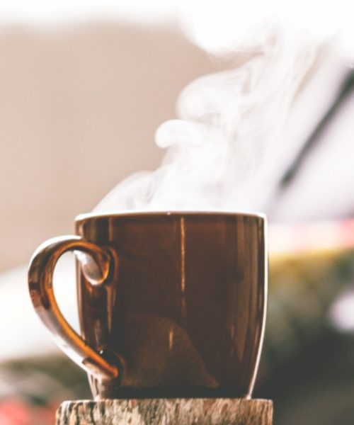 A brown metallic mug with steam coming out of it, with a slightly blurred background